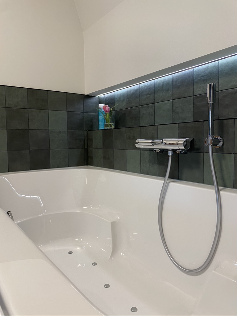 Badkamer met bubbelbad en donkere tegels