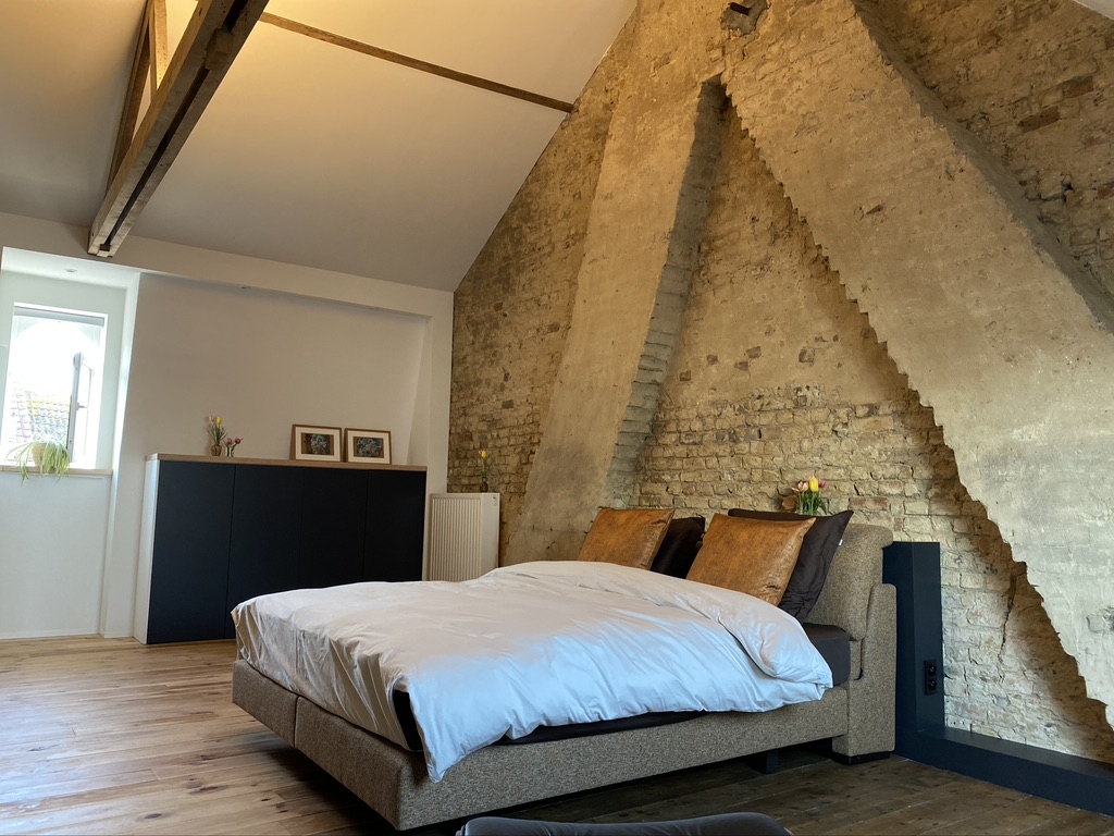 Slaapkamer met historische bakstenen muur en warm licht